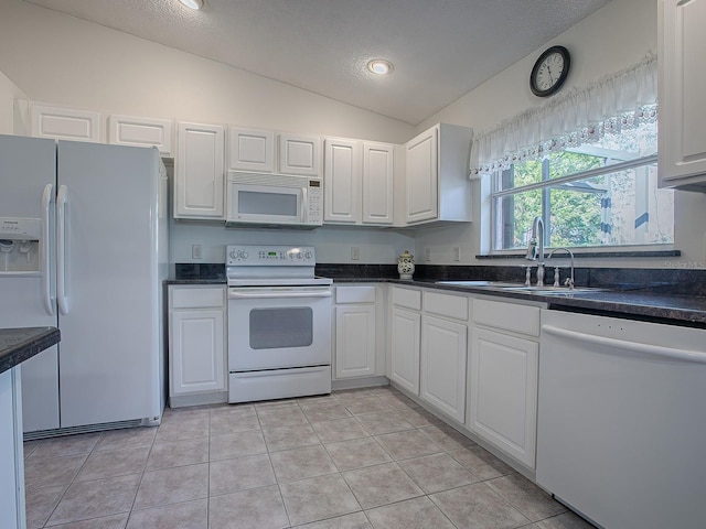 33236 Grand Cypress Way, Leesburg, FL 34748 - kitchen with white appliances, vaulted ceiling, a sink, white cabinets, and light tile patterned flooring