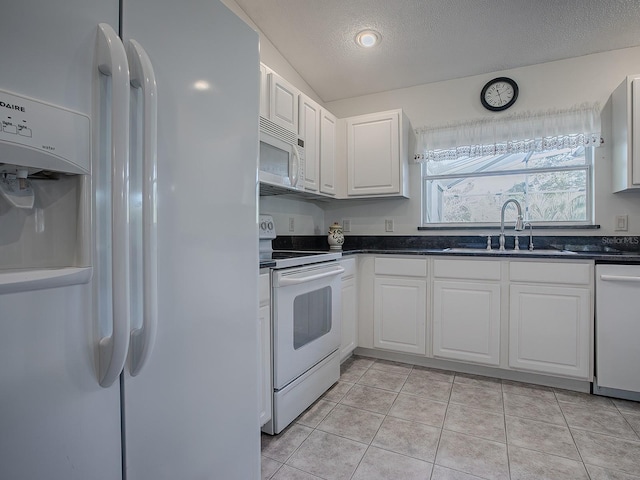 kitchen featuring white appliances, white cabinets, sink, light tile patterned floors, and a textured ceiling