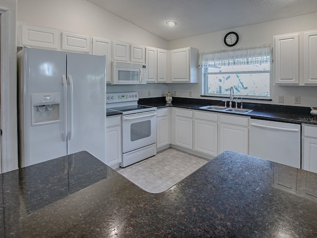 kitchen with white appliances, white cabinetry, and vaulted ceiling