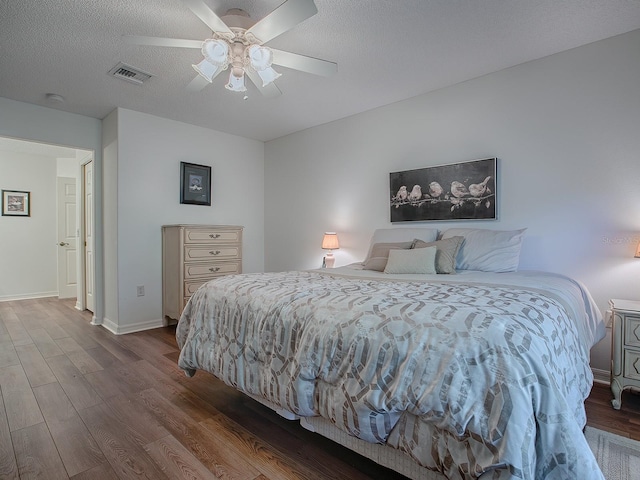 bedroom with hardwood / wood-style floors, a textured ceiling, and ceiling fan