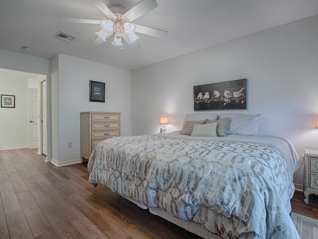 33236 Grand Cypress Way, Leesburg, FL 34748 - bedroom with dark wood-type flooring, a ceiling fan, and baseboards