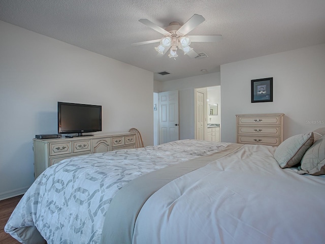 bedroom with ceiling fan, hardwood / wood-style floors, ensuite bathroom, and a textured ceiling