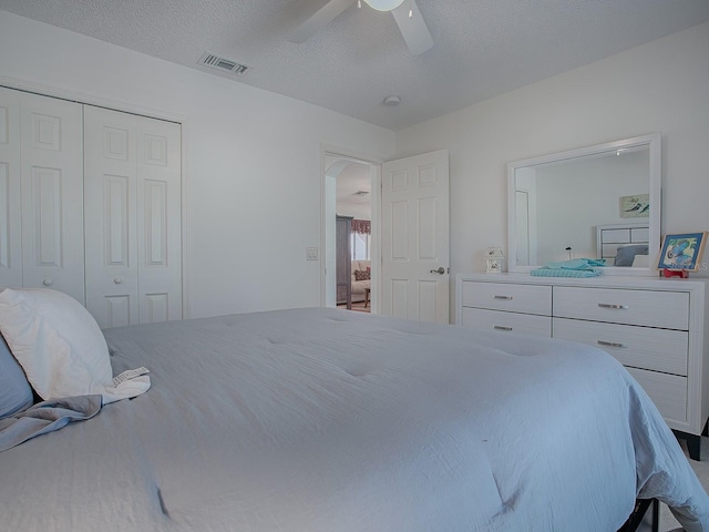 33236 Grand Cypress Way, Leesburg, FL 34748 - bedroom featuring a closet, a ceiling fan, arched walkways, and a textured ceiling