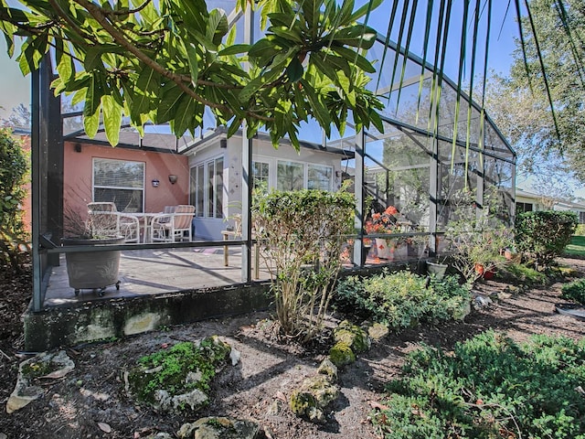 rear view of house featuring glass enclosure and a patio area