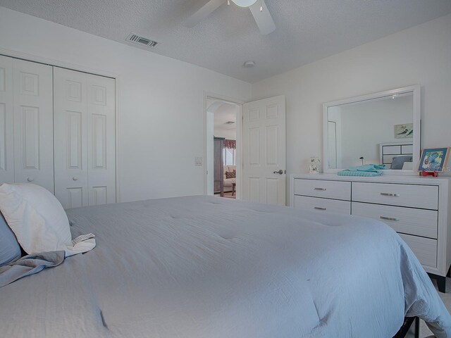 33236 Grand Cypress Way, Leesburg, FL 34748 - bedroom with a closet, a ceiling fan, arched walkways, and a textured ceiling