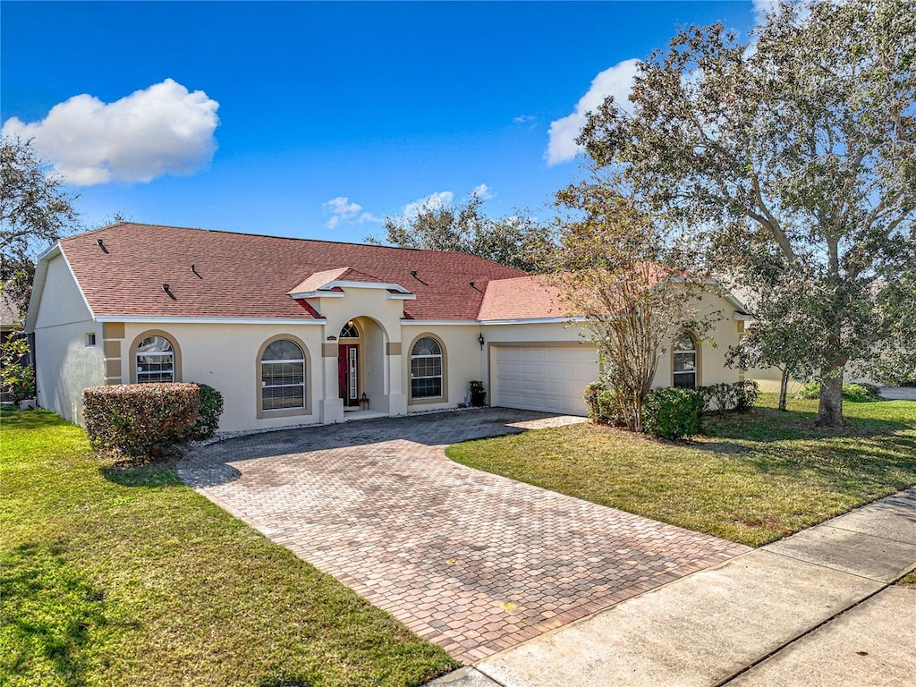 mediterranean / spanish-style home with a garage and a front lawn