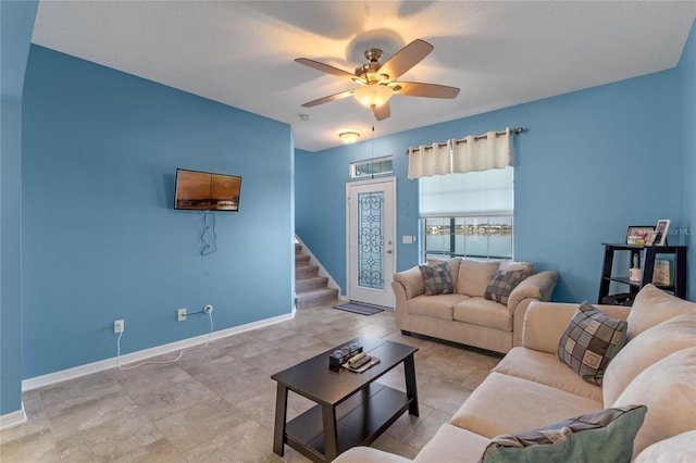 living area featuring stairs, ceiling fan, and baseboards