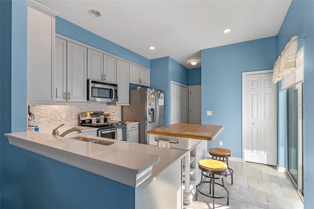 kitchen with recessed lighting, a kitchen island, a sink, appliances with stainless steel finishes, and decorative backsplash