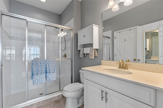 full bathroom with toilet, a stall shower, and vanity