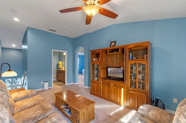 living room featuring arched walkways, lofted ceiling, light carpet, visible vents, and baseboards