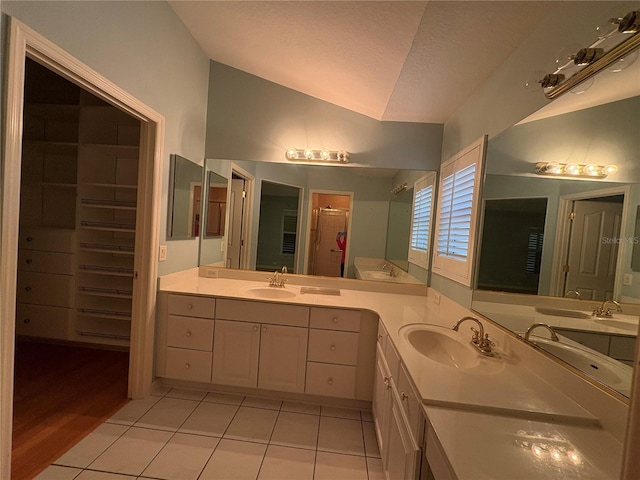 bathroom with tile patterned floors, a textured ceiling, vanity, and lofted ceiling