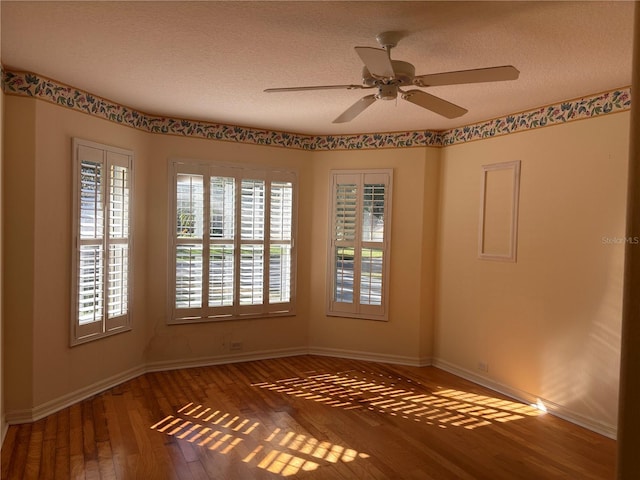 spare room with dark hardwood / wood-style floors, ceiling fan, and a textured ceiling