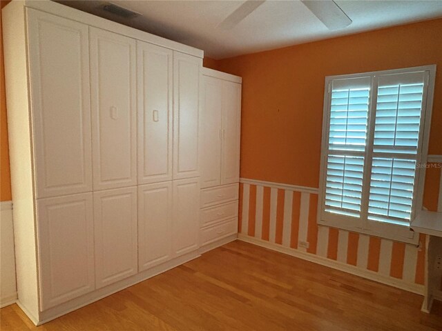 unfurnished bedroom with ceiling fan, light wood-type flooring, and a closet