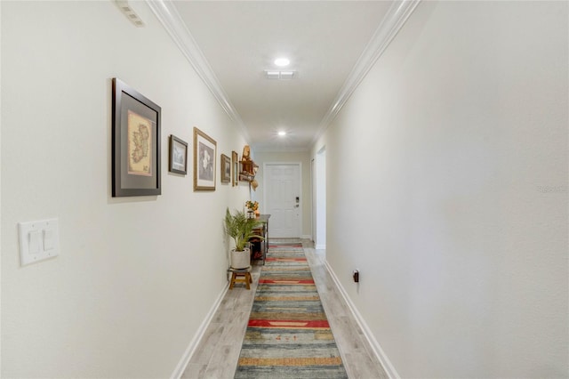 corridor with light hardwood / wood-style floors and ornamental molding