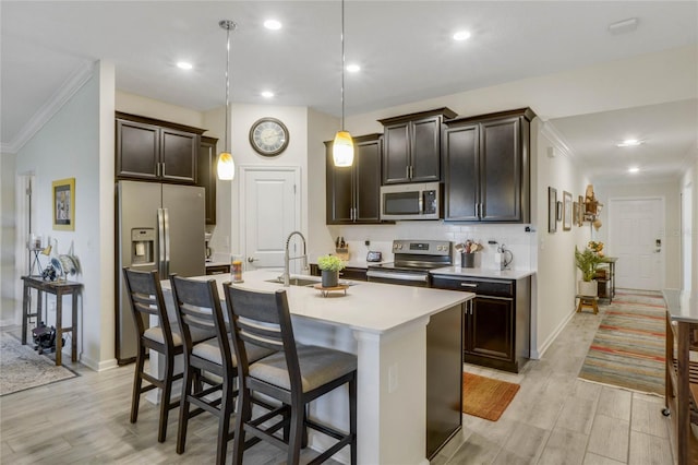 kitchen featuring sink, hanging light fixtures, an island with sink, a breakfast bar, and appliances with stainless steel finishes