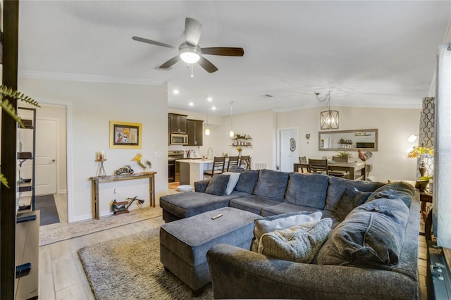 living room with ceiling fan with notable chandelier, vaulted ceiling, crown molding, sink, and light hardwood / wood-style flooring