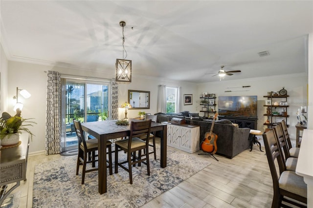 dining room with ceiling fan, light wood-type flooring, and crown molding