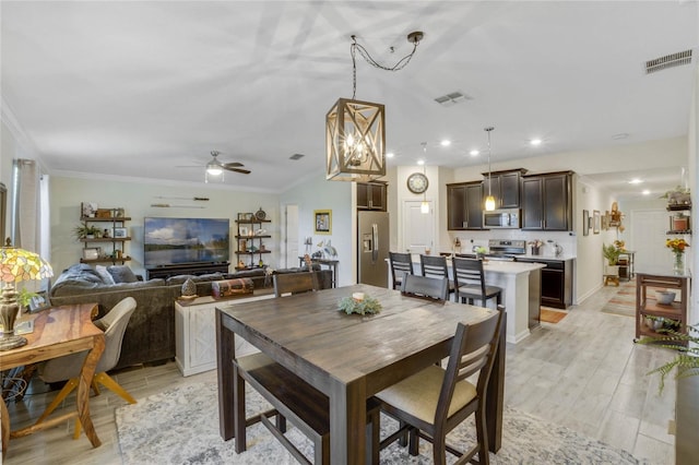 dining space with light hardwood / wood-style flooring, ceiling fan with notable chandelier, and ornamental molding