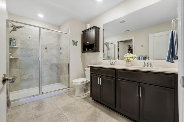 bathroom with tile patterned floors, vanity, a shower with shower door, and toilet