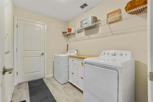 washroom with cabinets, washer and dryer, and light hardwood / wood-style floors