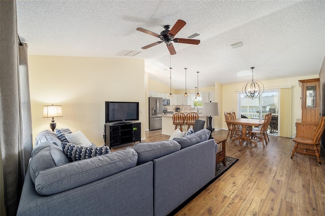 living room featuring ceiling fan with notable chandelier, a textured ceiling, light wood-type flooring, and lofted ceiling