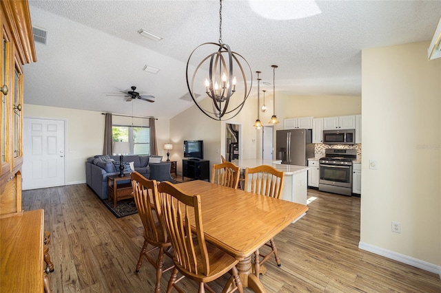 dining room featuring a textured ceiling, ceiling fan with notable chandelier, vaulted ceiling, and hardwood / wood-style flooring