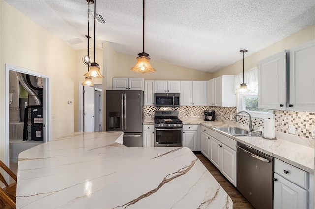 kitchen with stainless steel appliances, vaulted ceiling, hanging light fixtures, and sink