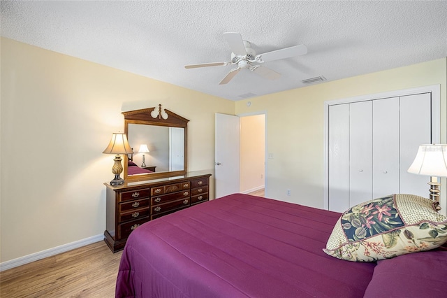 bedroom featuring a textured ceiling, light hardwood / wood-style floors, a closet, and ceiling fan