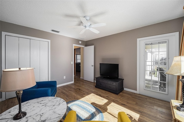 living room with ceiling fan, dark hardwood / wood-style flooring, and a textured ceiling