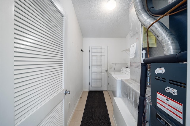 laundry room with washing machine and clothes dryer, light tile patterned flooring, and a textured ceiling