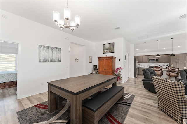 dining area with light hardwood / wood-style floors and a chandelier