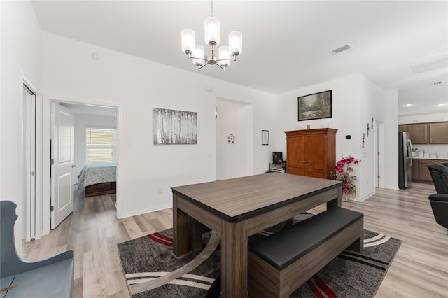 dining room with light hardwood / wood-style floors and a notable chandelier