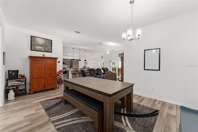 dining area with light hardwood / wood-style floors and ceiling fan with notable chandelier