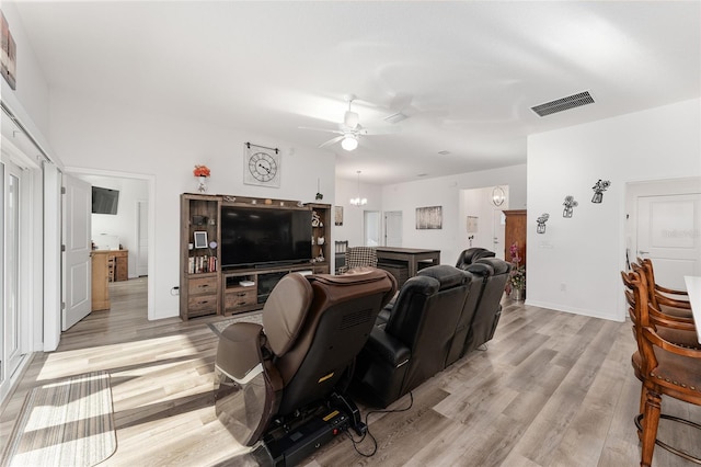 living room featuring ceiling fan with notable chandelier and light hardwood / wood-style floors