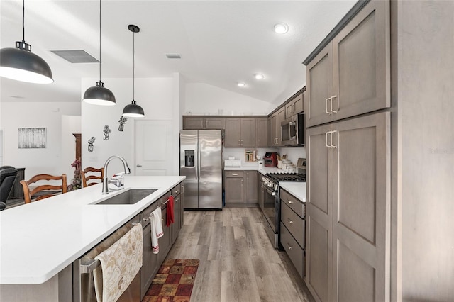 kitchen featuring lofted ceiling, sink, light hardwood / wood-style flooring, decorative light fixtures, and stainless steel appliances