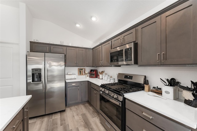 kitchen with dark brown cabinets, lofted ceiling, appliances with stainless steel finishes, and light hardwood / wood-style flooring