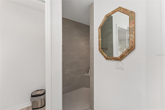 bathroom featuring a tile shower and a textured ceiling