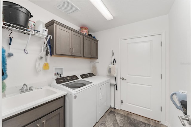 laundry room featuring cabinets, a textured ceiling, washing machine and dryer, and sink