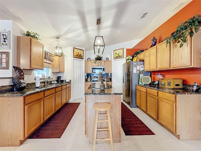 kitchen with stainless steel appliances, sink, light tile patterned floors, a kitchen island, and hanging light fixtures