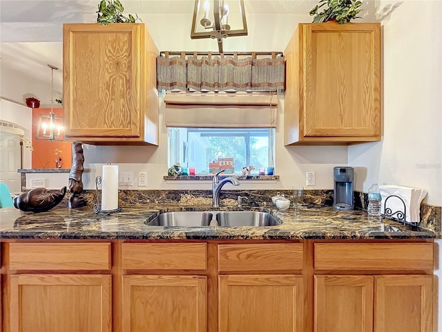 kitchen with dark stone countertops, sink, and pendant lighting