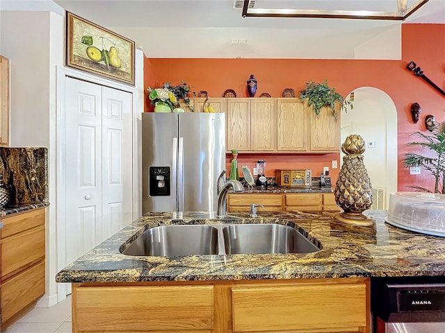 kitchen featuring appliances with stainless steel finishes, light tile patterned floors, dark stone countertops, and sink