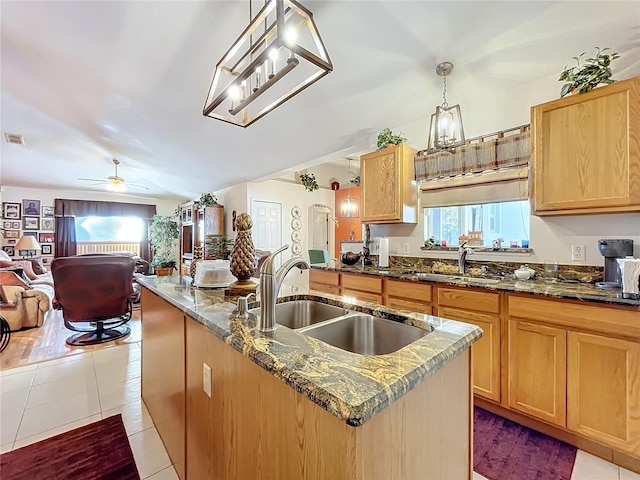 kitchen featuring ceiling fan, sink, light tile patterned floors, decorative light fixtures, and a kitchen island