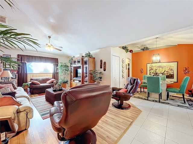 living room featuring ceiling fan, light tile patterned flooring, a textured ceiling, and vaulted ceiling