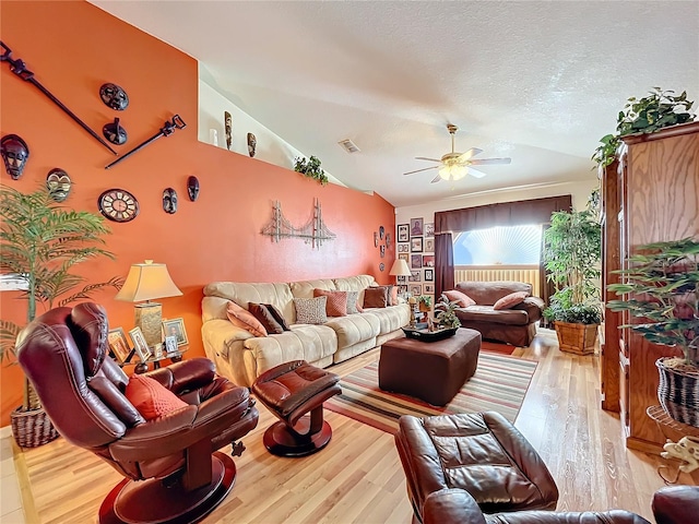 living room with a textured ceiling, ceiling fan, light hardwood / wood-style flooring, and lofted ceiling