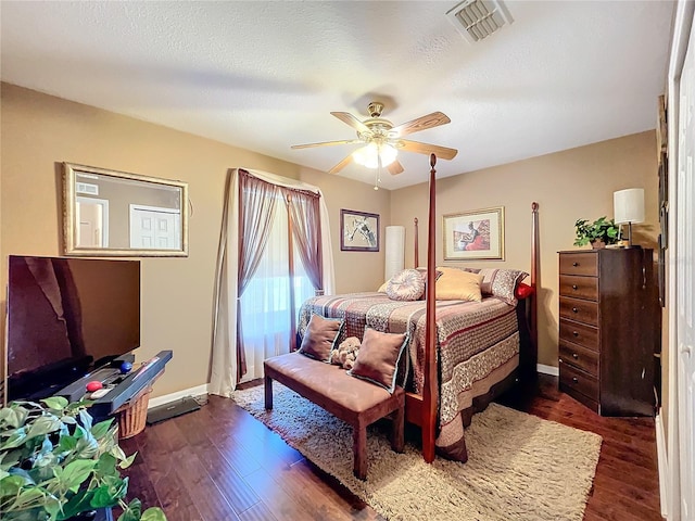 bedroom with a textured ceiling, ceiling fan, and dark hardwood / wood-style floors