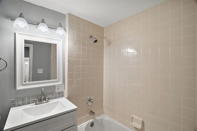 bathroom with vanity, tiled shower / bath combo, and a textured ceiling