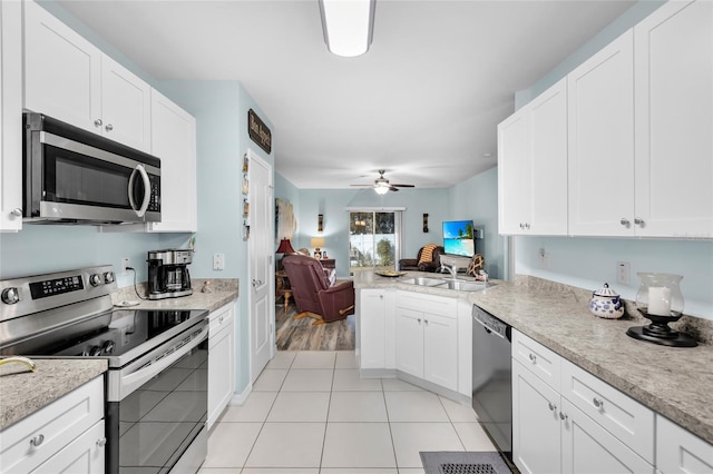 kitchen with sink, ceiling fan, light tile patterned floors, appliances with stainless steel finishes, and white cabinetry