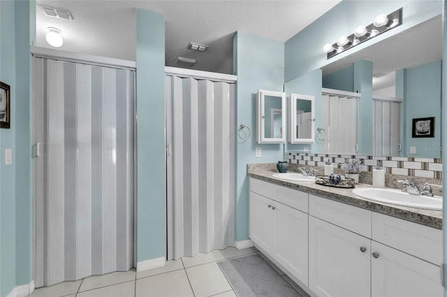 bathroom with tasteful backsplash, tile patterned floors, vanity, and a textured ceiling