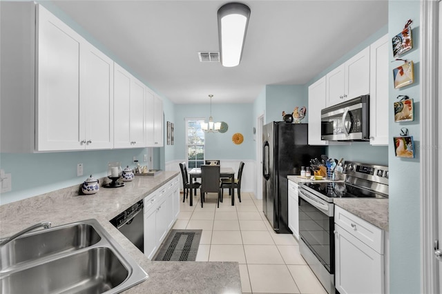 2354 Valhalla Dr, Tavares, FL 32778 - kitchen with stainless steel appliances, white cabinets, a chandelier, light countertops, and light tile patterned floors