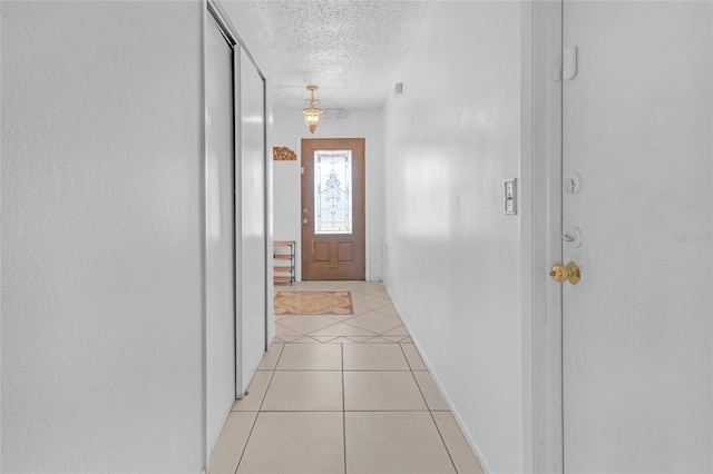 doorway featuring light tile patterned flooring and a textured ceiling